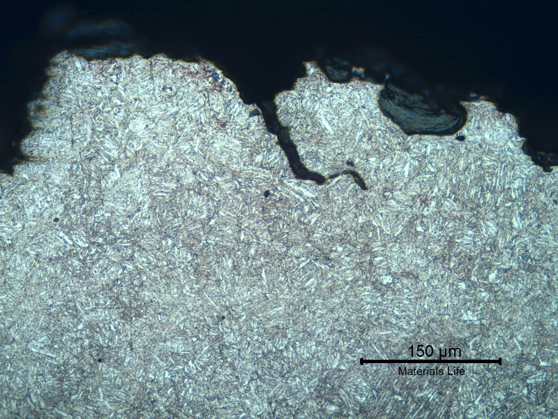 Micrographic detail of a transverse section, at the fracture (in the top of the figure). The fracture is brittle and follows the voids at interdendritic spaces, with secondary cracks.