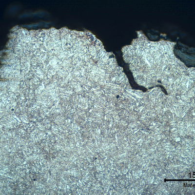 Micrographic detail of a transverse section, at the fracture (in the top of the figure). The fracture is brittle and follows the voids at interdendritic spaces, with secondary cracks.