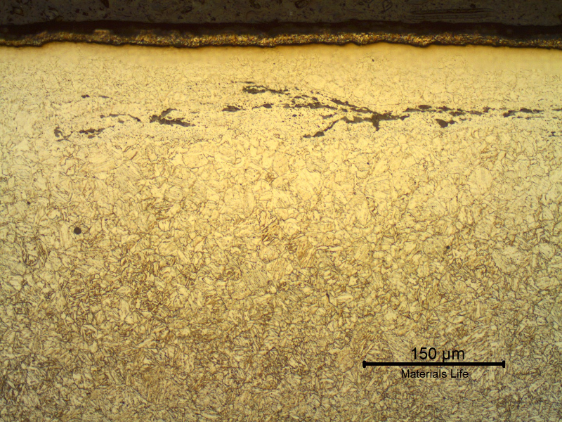 Ferritic-bainitic microstructure in the transverse section of the nut, at the surface where the cadmium plate is also evident. The nut surface presents a decarburized layer and the lap entrapped oxides.