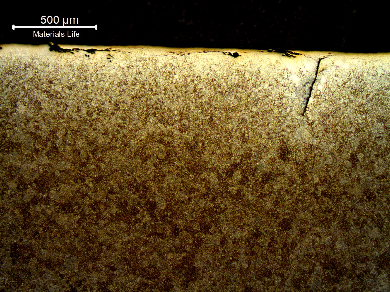 Micrography of the nut in a section transverse to the surface indication. There are several microcracks (parallel and perpendicular to the nut surface) filled with oxides.  The nut presented a martensitic microstructure in the center of the thickness and a ferritic-bainitic microstructure at surface and adjacent to the defect, due to decarburization occurred during high temperature forging.