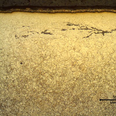 Ferritic-bainitic microstructure in the transverse section of the nut, at the surface where the cadmium plate is also evident. The nut surface presents a decarburized layer and the lap entrapped oxides.