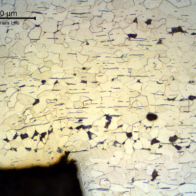 Micrographic detail of the longitudinal section of the fitting at the thread, showing a crack at the bottom of the thread.
