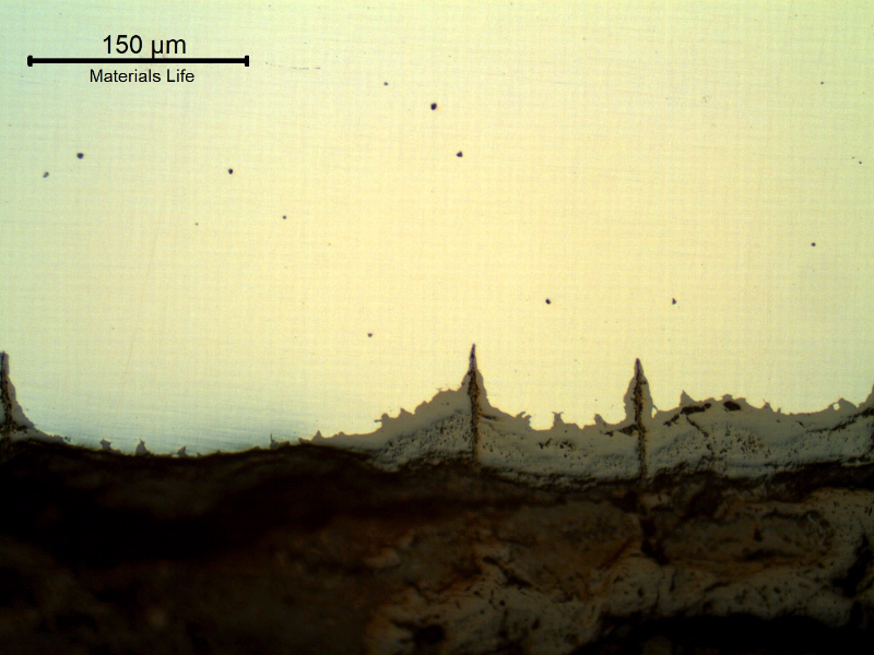 Micrographic details of the longitudinal section of the tube, close to ID, showing paralel cracks, filled with oxides, perpendicular to the surface.