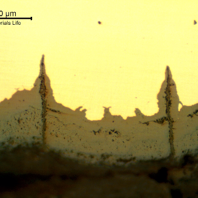 Micrographic details of the longitudinal section of the tube, close to ID, showing paralel cracks, filled with oxides, perpendicular to the surface.