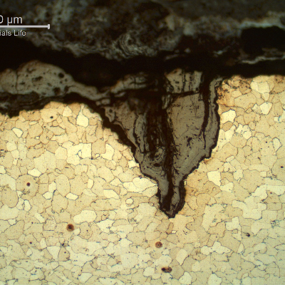 Micrography of the longitudinal section of the tube, close to OD, showing the cracks from the surface.  The cracks are filled with oxides and slightly opened by corrosion.