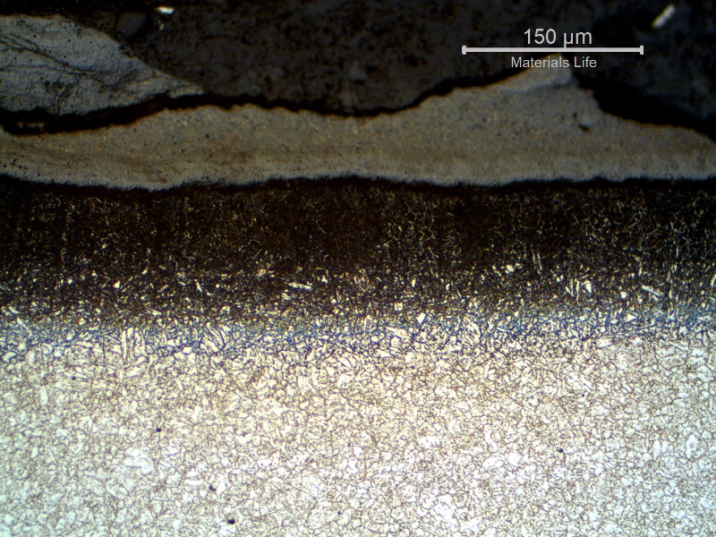 Micrography of the longitudinal section of the tube, close to the external surface. 
A scale  is evident at the surface as well as a carburizing layer.