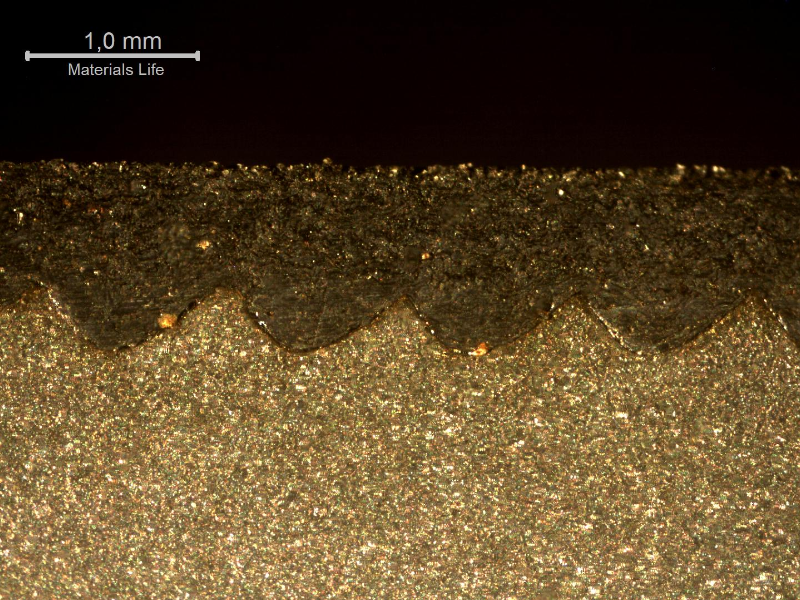 Macrographic detail of the thermal spray layer in a position of the shaft where it was not detached. Longitudinal section of the shaft. The waves are the machining marks created to anchor the thermal spray layer, that is about 1.5mm thick.