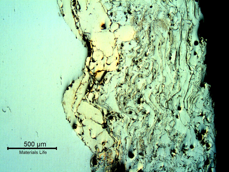 Micrography of the thermal spray (TS) layer showing the different alloys, gray oxides and black voids. 
The Ni base TS alloy is of a yellow colour at the interface with the shaft substrate (in the left).
The Cr base TS alloy appears white, similar to the shaft substrate. Longitudinal section of the shaft.