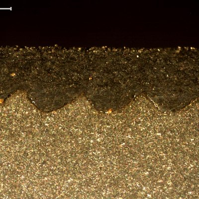 Macrographic detail of the thermal spray layer in a position of the shaft where it was not detached. Longitudinal section of the shaft. The waves are the machining marks created to anchor the thermal spray layer, that is about 1.5mm thick.