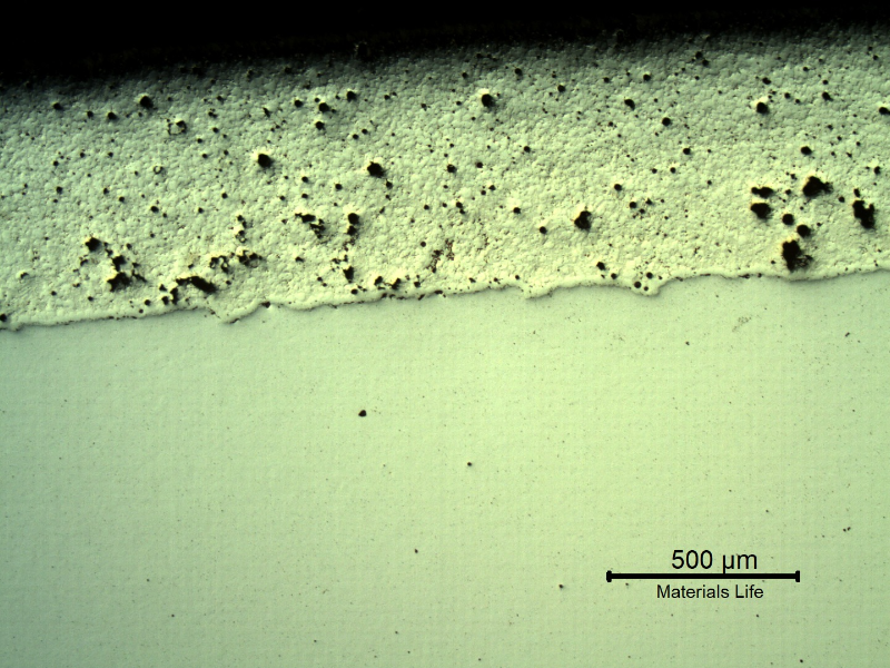 Micrography, as polished, of the transverse section of the forged pin with the layer applied by a (thermal) spray and fuse process.  The structure of the layer that is 0.7 mm thick, presented entrapped pores and globular oxides.  The layer was melted after application by thermal spray (in this case using a flame) and the pin was quenched and tempered after the full application and melting of the layer.