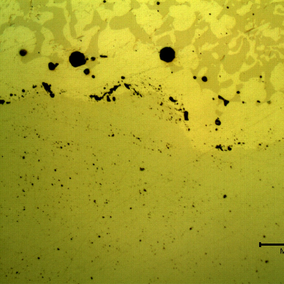 Micrographic detail, as polished, of the transverse section of the forged pin at the interface between the pin and the spray and fuse layer. The pin was heat treated after the thermal spray, and fuse treatment. 
The interface presents a higher concentration of globular oxides and pores, entrapped.