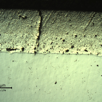 Micrography, as polished, of the transverse section of the forged pin, showing a crack in the thermal spray layer, thickness about 0.8mm. The spray and fuse process was conducted in a low alloy steel, type AISI 4130, but the quenching and tempering heat treatment was not applied later, and the pin body presented low strenght, evidencing plastic deformation after hydrostatic testing, that cause the layer cracking.