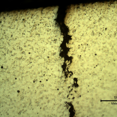Micrographic detail of the crack in the thermal spray layer. The spray and fuse layer presented a typically melted structure with entrapped pores and globular oxides.