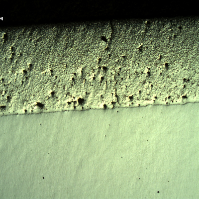 Micrography, as polished, of the transverse section of the forged pin with the layer applied by a (thermal) spray and fuse process. The layer presented entrapped pores and globular oxides. It was melted after application by thermal spray (in this case using a flame) but the pin was not heat treated after the full application and melting of the layer and the base metal is ferritc-pearlitic.