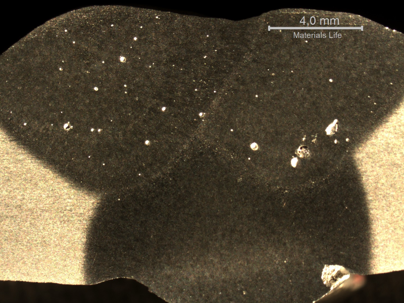 Macrographic detail of the overhead position welded joint, showing the three passes. The shining spots are pores, some of a large size.