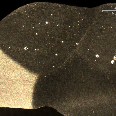 Macrographic detail of the overhead position welded joint, showing the three passes. The shining spots are pores, some of a large size.