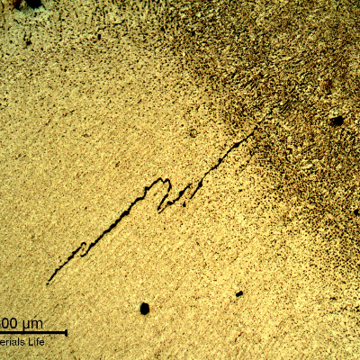 Micrography of the welded joint, at the root, presenting hot cracks.  The imposed high energy in the root due to the ceramic backing support created a condition for cracking.