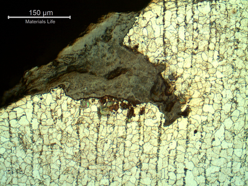 Micrographic detail of the crack at the edge of the tube.  This is not the best direction of analysis because the cracks are parallel to the analyzed section. It is possible to see the crack from the surface, large and filled with oxides.