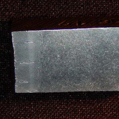 The macrography of the surface exposed to the combustion chamber presents multiple cracks, perpendicular to the internal diamater of the tube (left side of the figure).  The cracks are located in the tube and propagated into the tube wall and welded joint to the plate (right side of the figure).