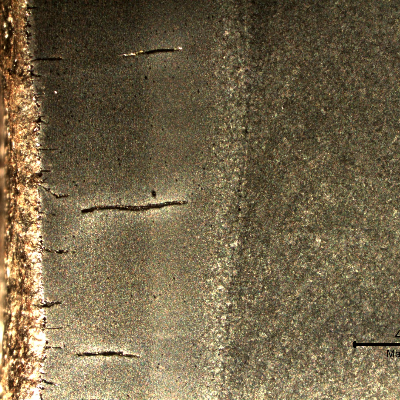 Higher magnification macrography (in a stereoscope) of the surface exposed to the combustion chamber, presenting multiple cracks perpendicular to the internal diamater of the tube (left side of the figure).  The cracks are located in the tube and propagated into the tube wall and welded joint.