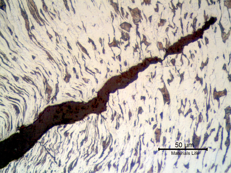 Micrographic detail of a longitudinal section of the bolt at the bottom of the thread fillet adjacent to the fracture, presenting a ductile cracking propagating with a plastic deformation.
The deformation lines of the cold formed process are also deformed by the cracking propagation and there are some other small secondary cracks at 90° from the principal cracking.