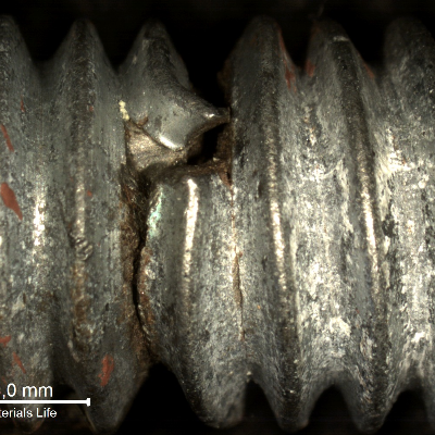 Detailed aspect of the eye bolt fracture position, with strong plastic deformation indicating ductile overloading. The red marks in the thread surface of the bolt (in the left side of the image) correspond to the position where the nut was tight. Thread fillets adjacent to the fracture presented secondary cracks.