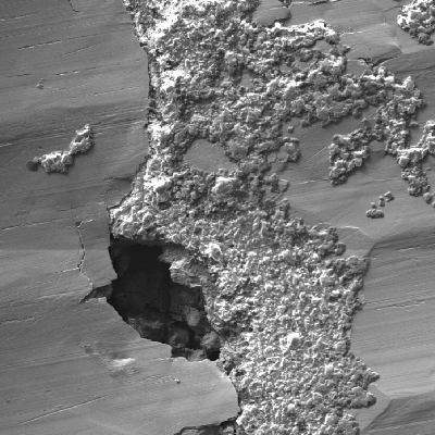 Microscopic details of the ring surface showing the fouling at the surface and localized corrosion under the deposits.