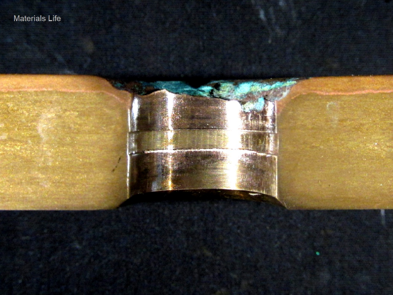 Macrographic detail of the transverse section of the tubesheet at the cooper alloy tube position, after removal of the 5/8" tube.  The red layer at the top of the plate (exposed to the cooling medium - treated seawater) is a region of selective corrosion, dezincification.