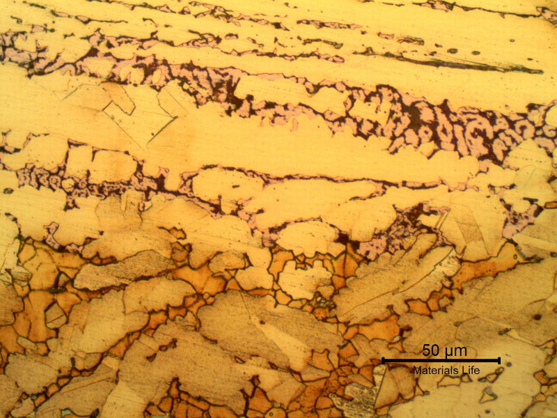 Micrography of the interface between the layer where the dezincification occurred (top of the figure) and the region where the material was not yet corroded (bottom of the figure, etched to reveal the microstructure).It is clear that the cracks (black opened regions in the upper side of the figure) are associated to the red islands that correspond to the regions of beta phase (orange islands in the bottom of the figure),