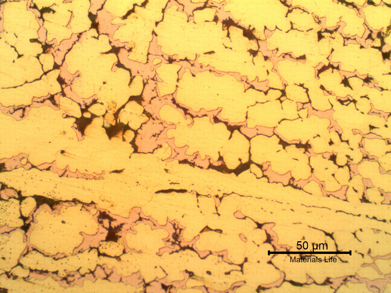 Micrographic detail of the corroded region of the tubesheet presenting a microstructure of alpha (light yellow ), but no longer beta. In the position of the beta phase it is possible to see the cooper rich island (light red) and cracks (black) due to the selective removal of the zinc.