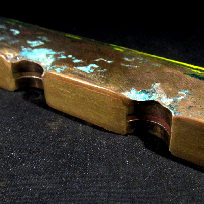 Transverse section of the tubesheet, after removal of the tubes.  The seawater sie is to the top of the figure.  It is possible to see regions of localized corrosion close to the tube position and a red layer all through the plate surface.
