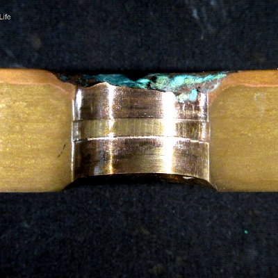 Macrographic detail of the transverse section of the tubesheet at the cooper alloy tube position, after removal of the 5/8" tube.  The red layer at the top of the plate (exposed to the cooling medium - treated seawater) is a region of selective corrosion, dezincification.