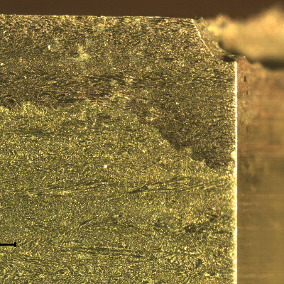 Macrographic detail of the transverse section of the tubesheet at the cooper alloy tube position, after removal of the 5/8" tube.  The "layer" at the top of the plate (exposed to the cooling medium - treated seawater) is a region of selective corrosion, dezincification.  It is possible to see that in the right side of the figure, where the cooper tube was positioned, the corrosion damage is deeper.
