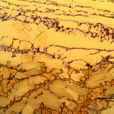 Micrography of the interface between the layer where the dezincification occurred (top of the figure) and the region where the material was not yet corroded (bottom of the figure, etched to reveal the microstructure).It is clear that the cracks (black opened regions in the upper side of the figure) are associated to the red islands that correspond to the regions of beta phase (orange islands in the bottom of the figure),