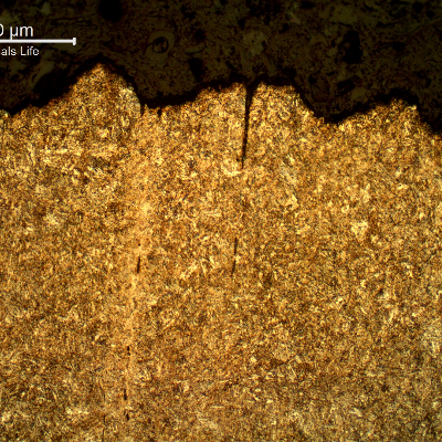 Micrography of the longitudinal section of the bolt, in the center of the thickness, showing at the fracture surface (top of the figure), secondary cracks that are perpendicular to the fracture, associated to segregation bands.