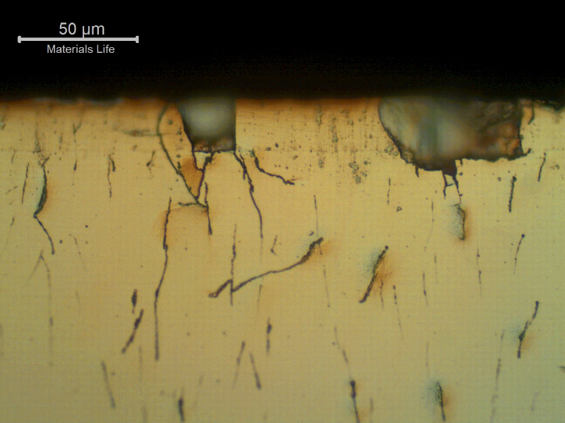 Micrographic aspect of the Cr layer at the surface presenting incipient damage.  Microcracks  of the Cr layer, associated to small pits.