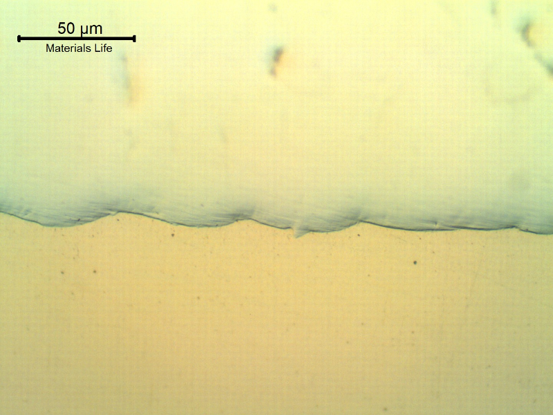 Micrography of the interface between the Ni layer (bottom) and the Cr layer (top of the figure).  The Cr layer, 250 microns thick and 1100HV hardness, presents small pores and cracks (that appear like black shadows, not focused).