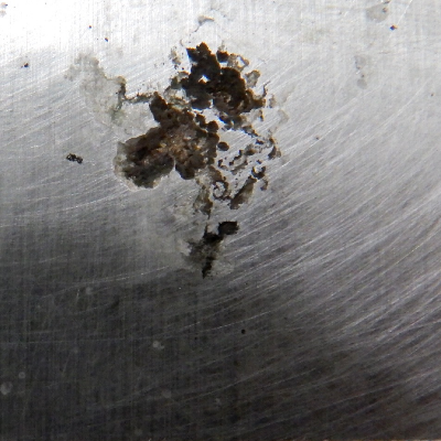 Aspect of the hydraulic cylinder surface presenting white stains and black oxides in a region that started a localized dissolution under deposit.