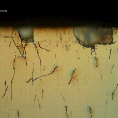 Micrographic aspect of the Cr layer at the surface presenting incipient damage.  Microcracks  of the Cr layer, associated to small pits.
