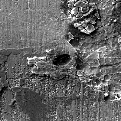 Scanning electron microscopy image of the chromium plated cylinder surface, presenting deposits and localized dissolution under deposits. There are different stages of corrosion in this region, observed in low magnification. Small areas of attack and a shallow pitting with deposits that were analyzed by EDS and revealed the presence of S.