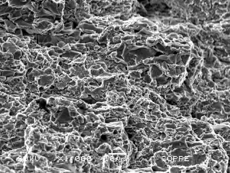 Fracture micromechanism at a region close to the external surface.  In this position the fracture shows quasecleavage, as well as decohesion of large carbides. typical of overloading this high strenght martensitic structure (64 HRc).