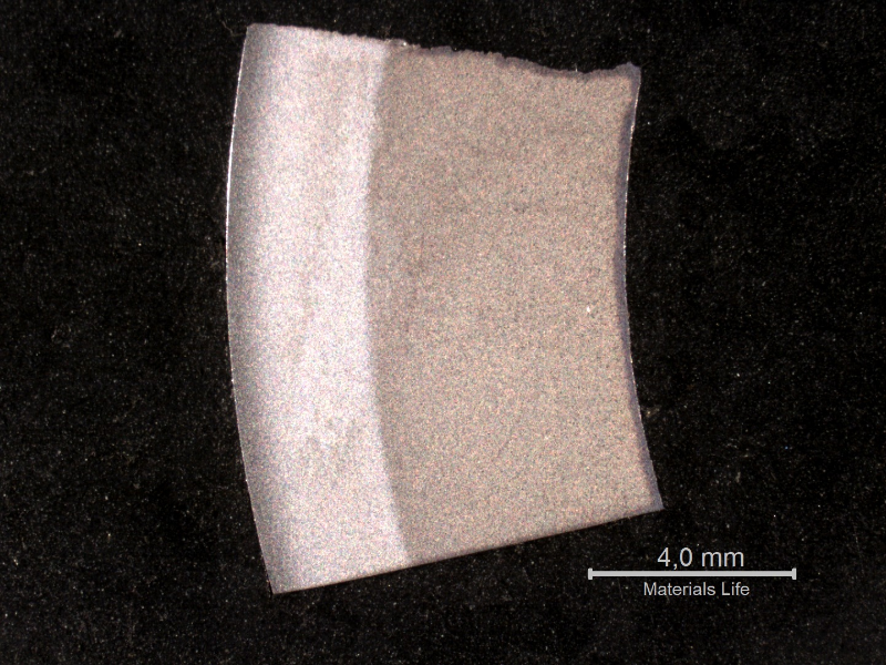 Macrography of a circumferential section of the roller bearing, showing two different structures: one, white and hard (64 HRc), close to the external surface; and the other, dark and soft (21 HRc), close to the internal surface. The hardness in the thickness, close to the interface, is about 50 HRc.