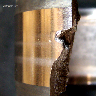 Aspect of the external surface of the broken cylindrical roller bearing presenting a polished external diameter and a the rupture with brittle characteristics (flat and parts that were lost).