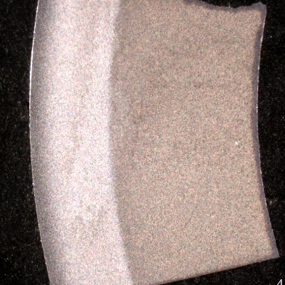 Macrography of a circumferential section of the roller bearing, showing two different structures: one, white and hard (64 HRc), close to the external surface; and the other, dark and soft (21 HRc), close to the internal surface. The hardness in the thickness, close to the interface, is about 50 HRc.