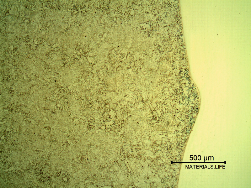 Micrography of a longitudinal section of the pipe at the overlay fusion line, with Nital etch that reveals only the low alloy steel structure, to the left side of the image.