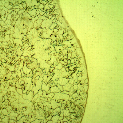 Micrography of a longitudinal section of the pipe at the overlay fusion line, with Nital etch that reveals only the low alloy steel structure, to the left side of the image.  Some decarburization of the low alloy steel substrate is evident since the microstructure is slightly different a little far from the interface.