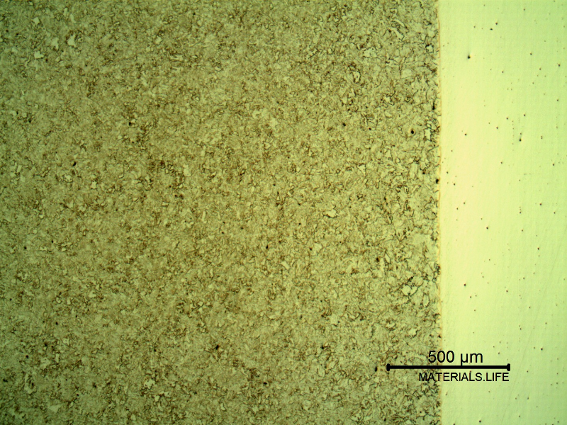 Micrography of a longitudinal section of the pipe at the interface with the clad plate, with Nital etch that reveals only the low alloy steel structure, to the left side of the image.