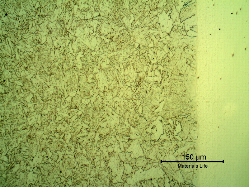Micrography of a longitudinal section of the pipe at the interface with the clad plate, with Nital etch that reveals only the low alloy steel structure, to the left side of the image.