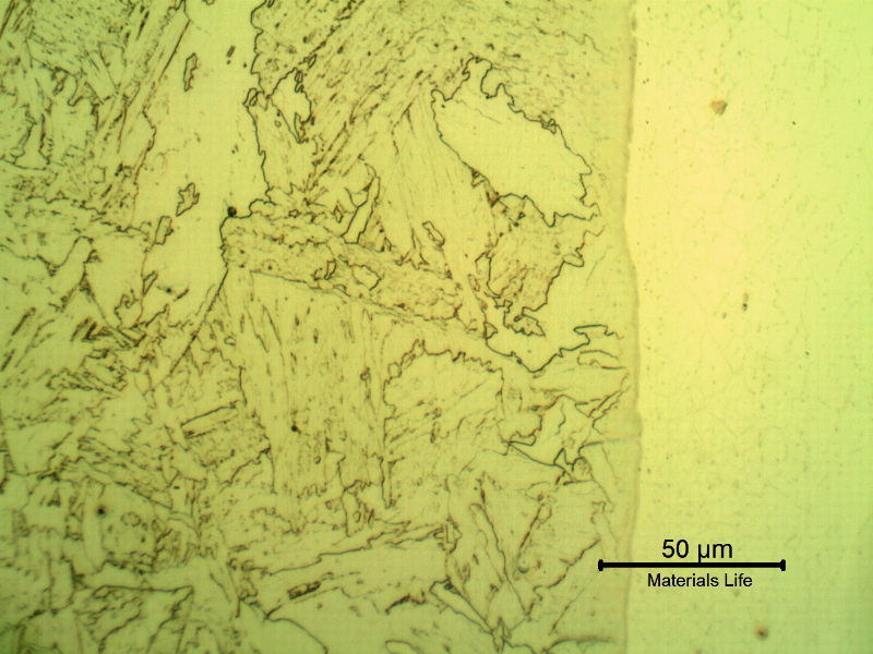 Micrographic detail of a longitudinal section of the pipe at the interface with the clad plate, with Nital etch that reveals only the low alloy steel structure, to the left side of the image.  The metallurgical bonding of the claded plate to the substrate is evident since there are no voids or defects.