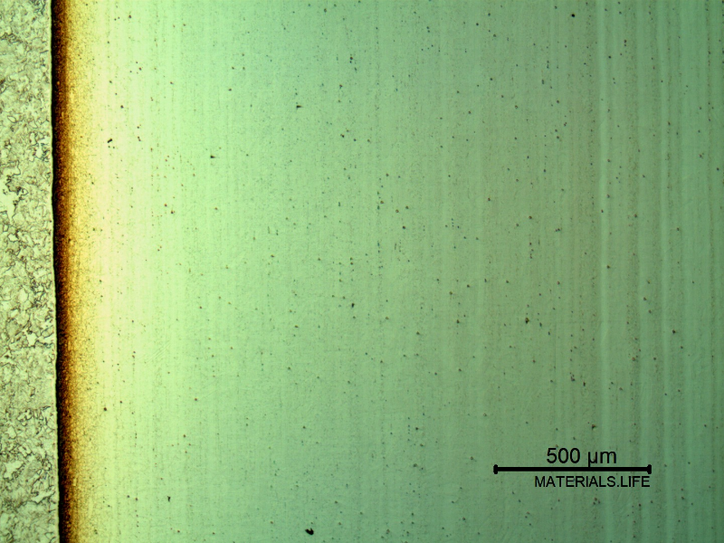 Low magnification micrography of a longitudinal section of the pipe at the interface with the clad plate, with electrolytic etch that reveals the clad plate structure (to the right side of the image), as well as the clad interface.